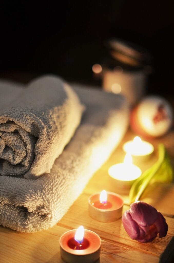 Rolled towels and tealight candles on a spa table, representing relaxation and indulgence.