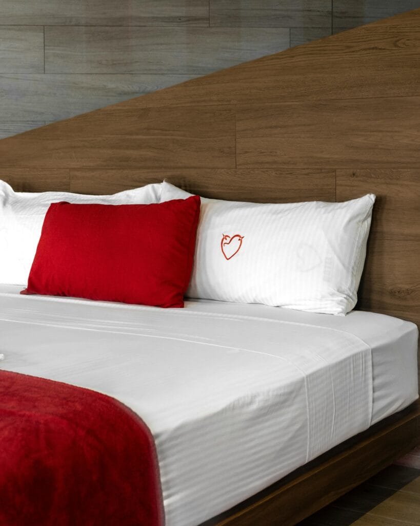 pexels-photo-28174031-28174031 Contemporary hotel room interior featuring a cozy bed with red accents and heart embroidery in Ciudad de México.